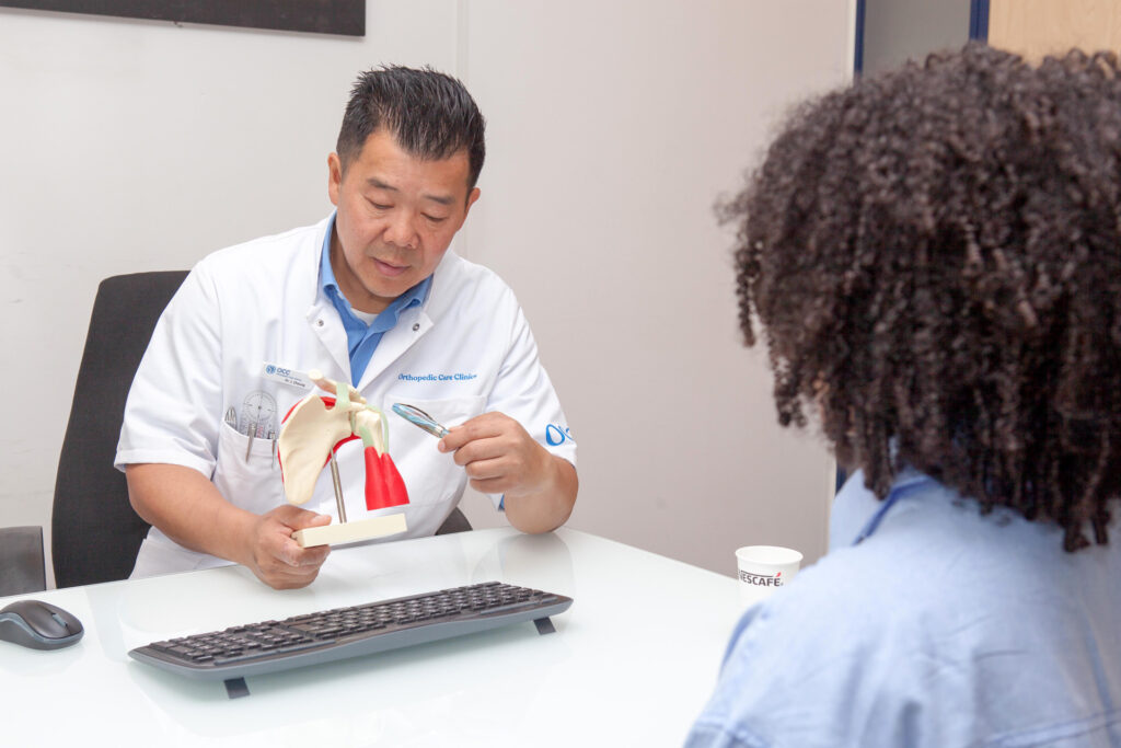 Orthopedisch chirurg laat schouder doorsnede zien met uitleg aan patient in Amsterdamse kliniek.